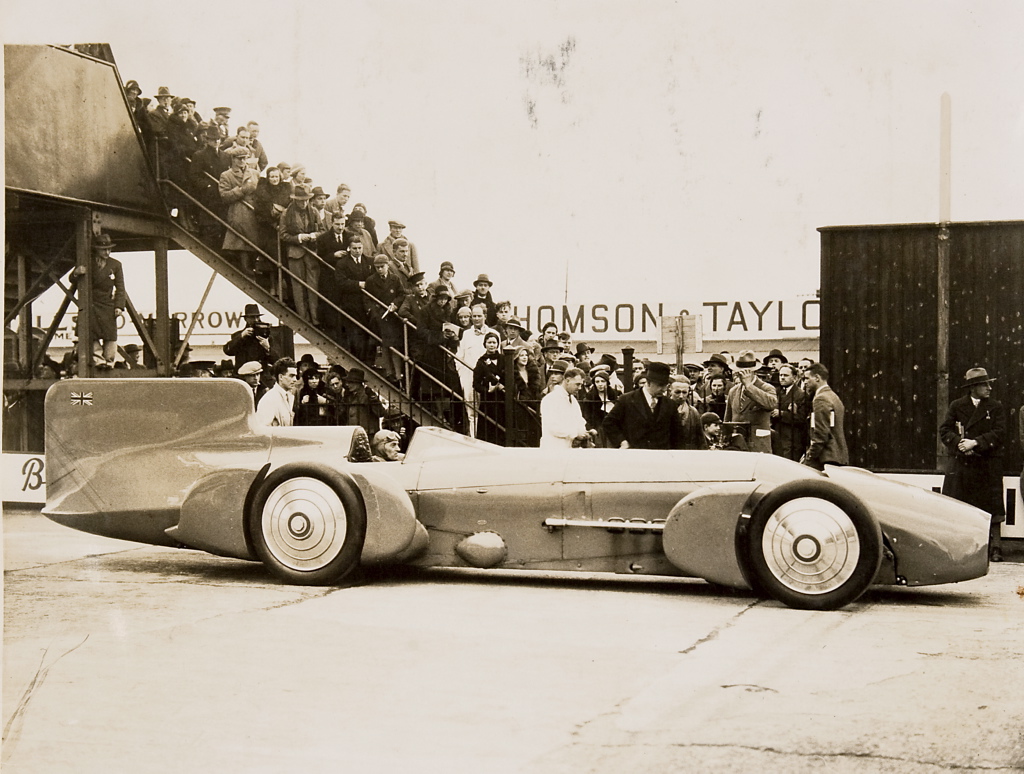 Sir malcolm campbell at the wheel of the bluebird with crowd 1926 1936